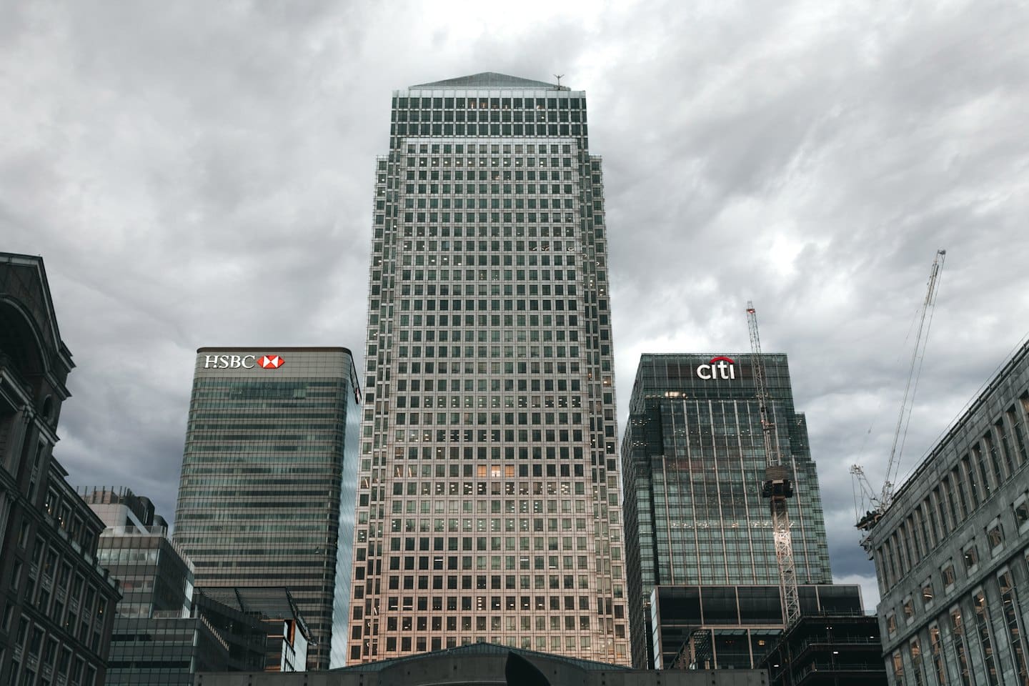 Modern skyscrapers ascend into a cloudy sky over a city.